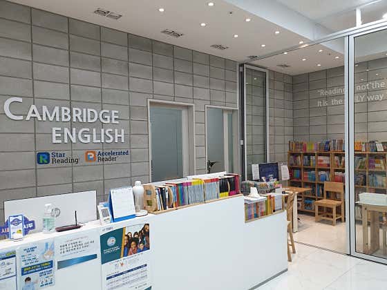 영어 원서가 비치된 캠브리지어학원 리셉션과 CAMBRIDGE ENGLISH 로고